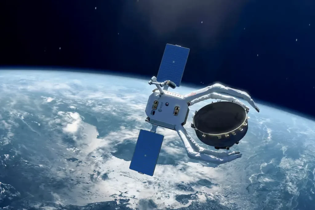 Satellite using robotic arms to capture space debris, with Earth visible in the background.